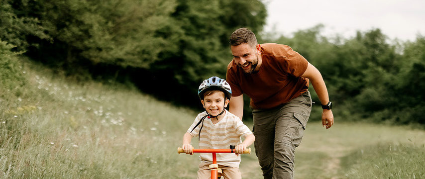 Pai correndo ao lado do filho de bicicleta